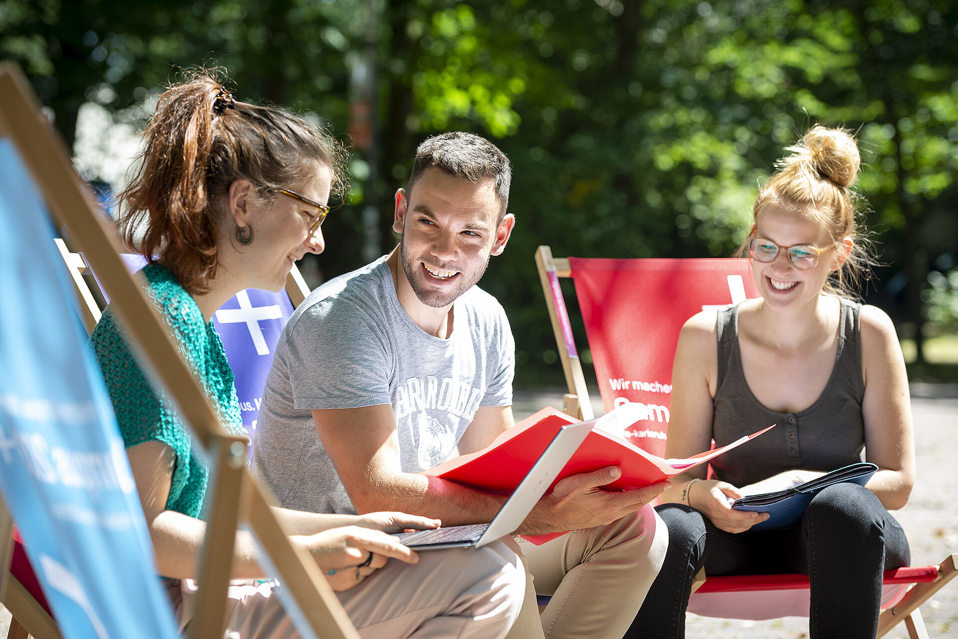 Studenten, die zusammen in der Sonne sitzen und lachen